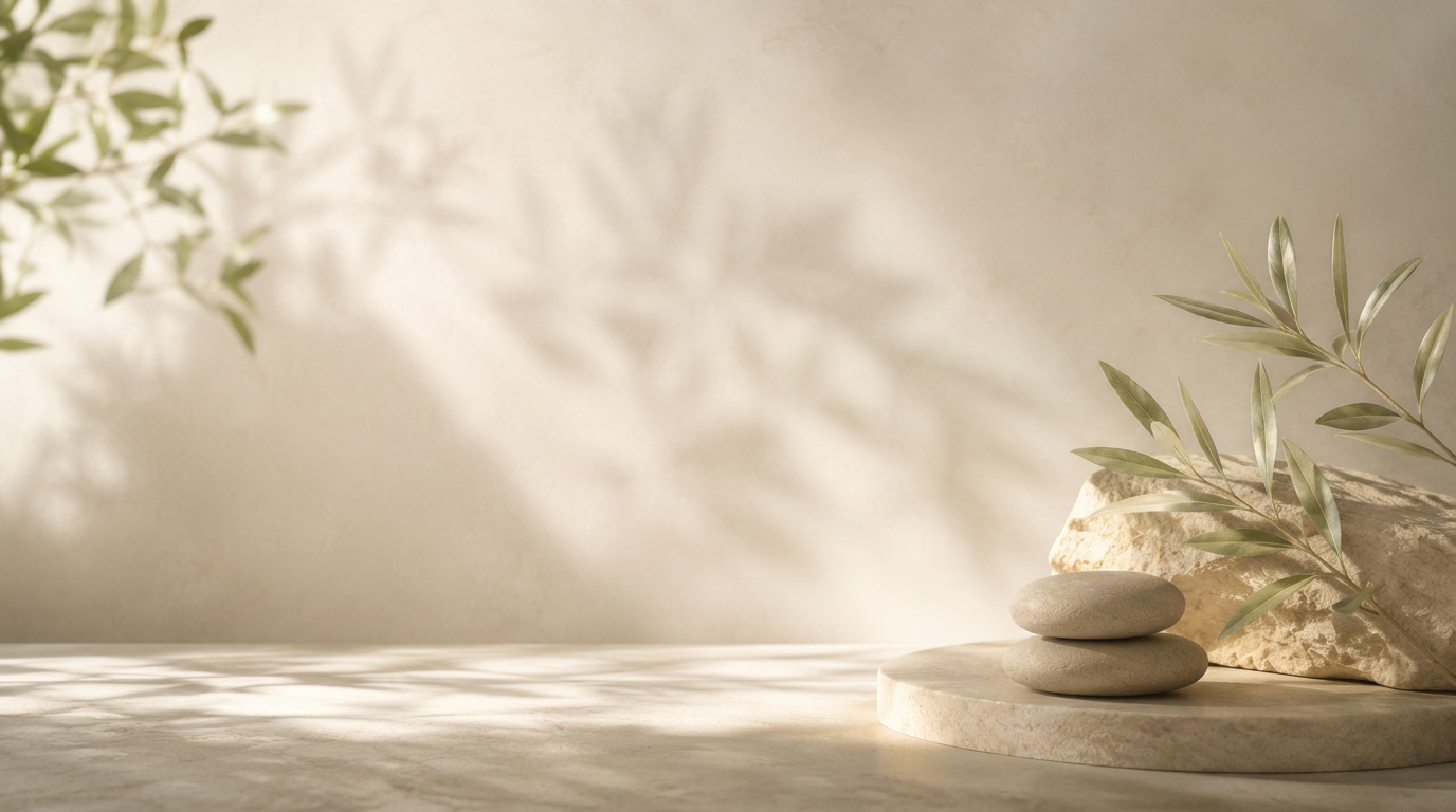 Serene spa scene with stacked river stones, olive branches, and soft leaf shadows on a warm cream wall